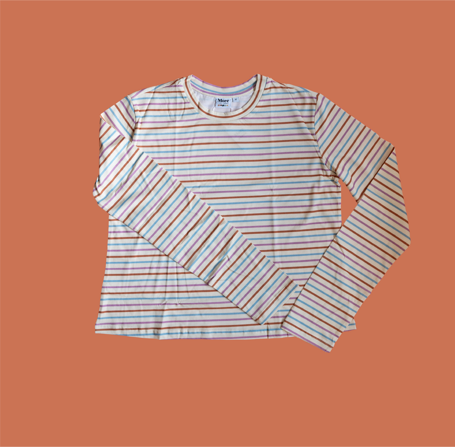 Flat lay image of More the label striped long sleeve top on burnt orange background.
