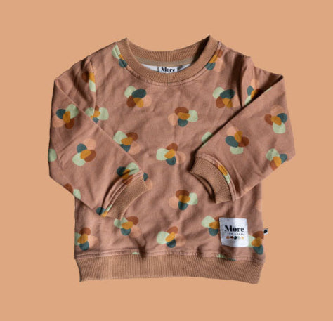 More The Label organic cotton children's clothing Stone Huddle Jumper flat lay image of front of garment on peach background. Garment features custom stone huddle print and More The Label logo.