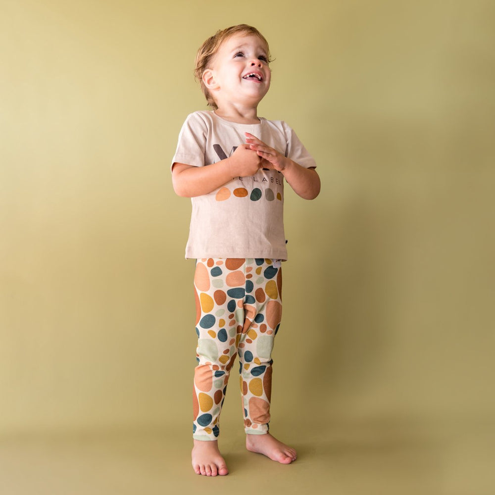 Image of child wearing stone print legging with logo tee in front of light green background.