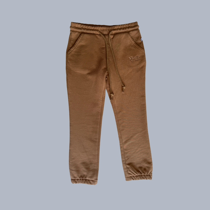 More The Label organic cotton children's clothing chocolate track pant flat lay image of front on a blue background. Brown track pants with elastic waste and drawstring. 