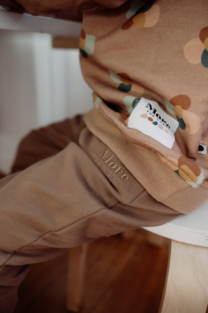 More The Label organic cotton children's clothing chocolate track pant worn by Henry with Stone Huddle Jumper, with More The Label logo patch. Brown track pants with elastic waste and drawstring. 
