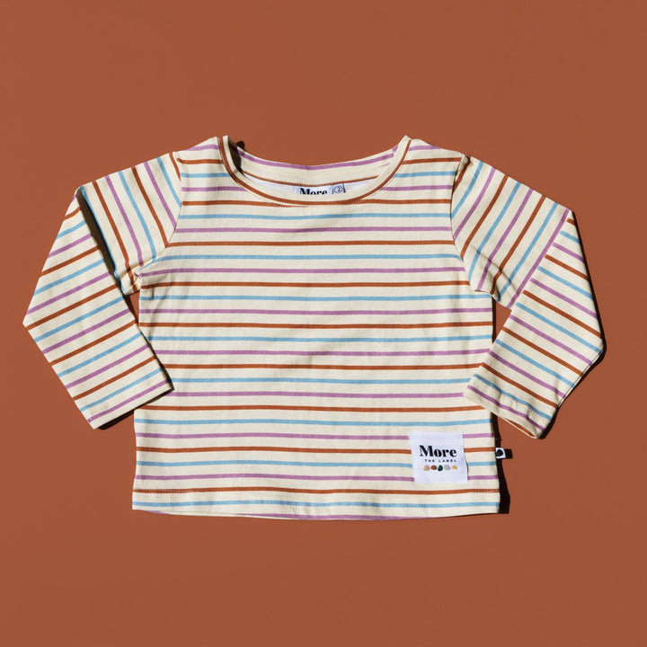 Flat lay image of More the label striped long sleeve tee on burnt red background.