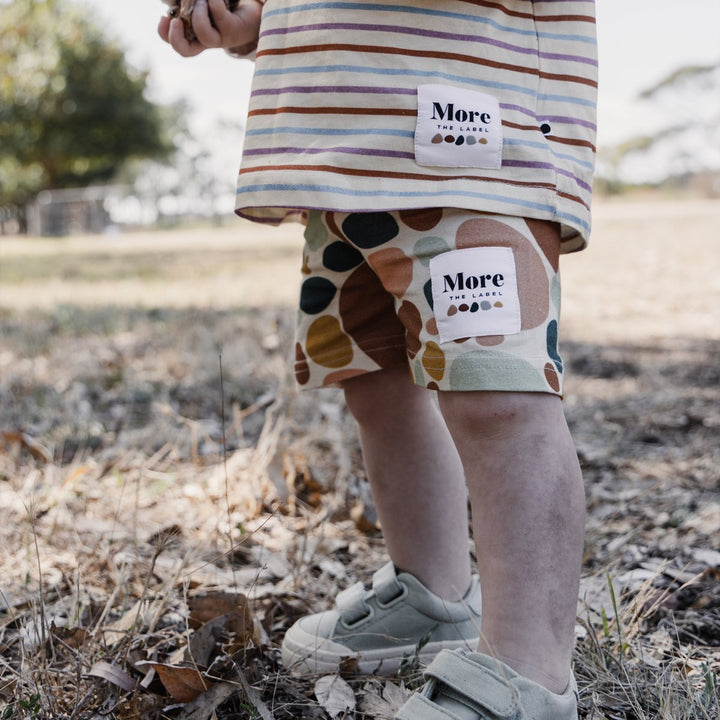 Close up image of one year old child wearing More the label stone print bike short with striped long sleeve tee.