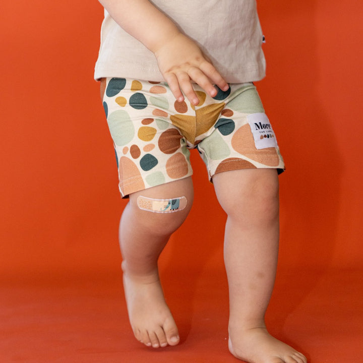 Close up image of one year old child wearing More the label stone print bike short with logo tee.