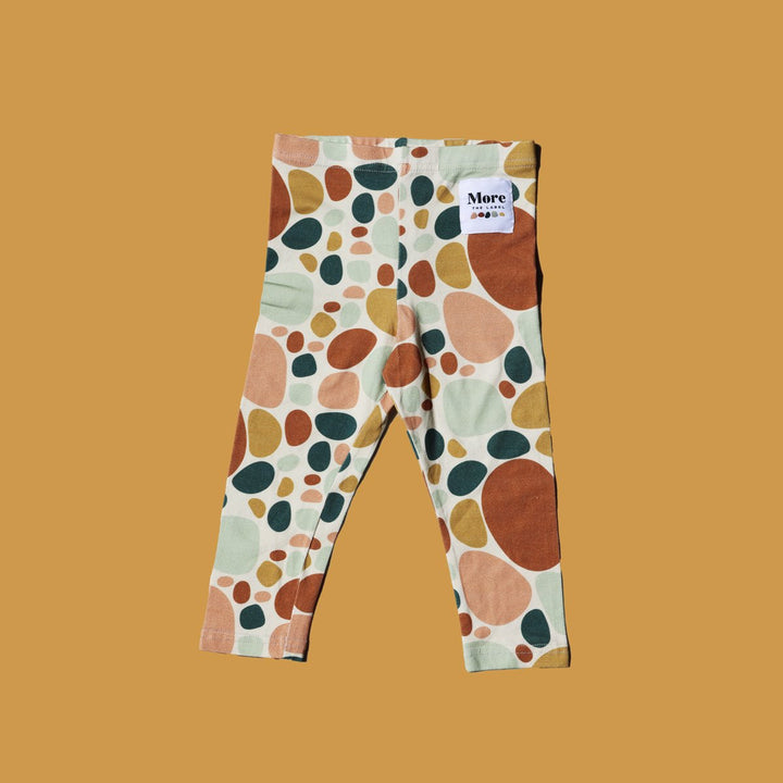 Flat lay image of More the label stone print legging on mustard background.
