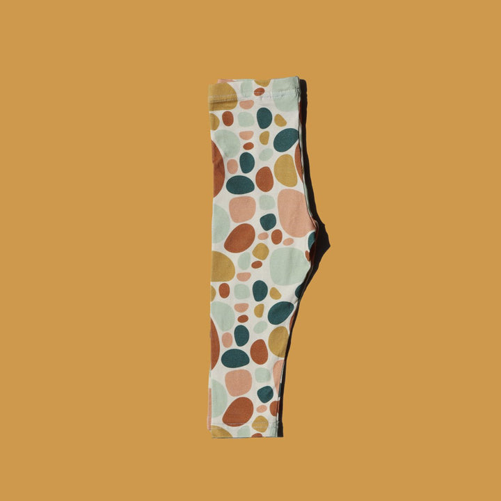 Flat lay image of More the label stone print legging folded in half on mustard background.