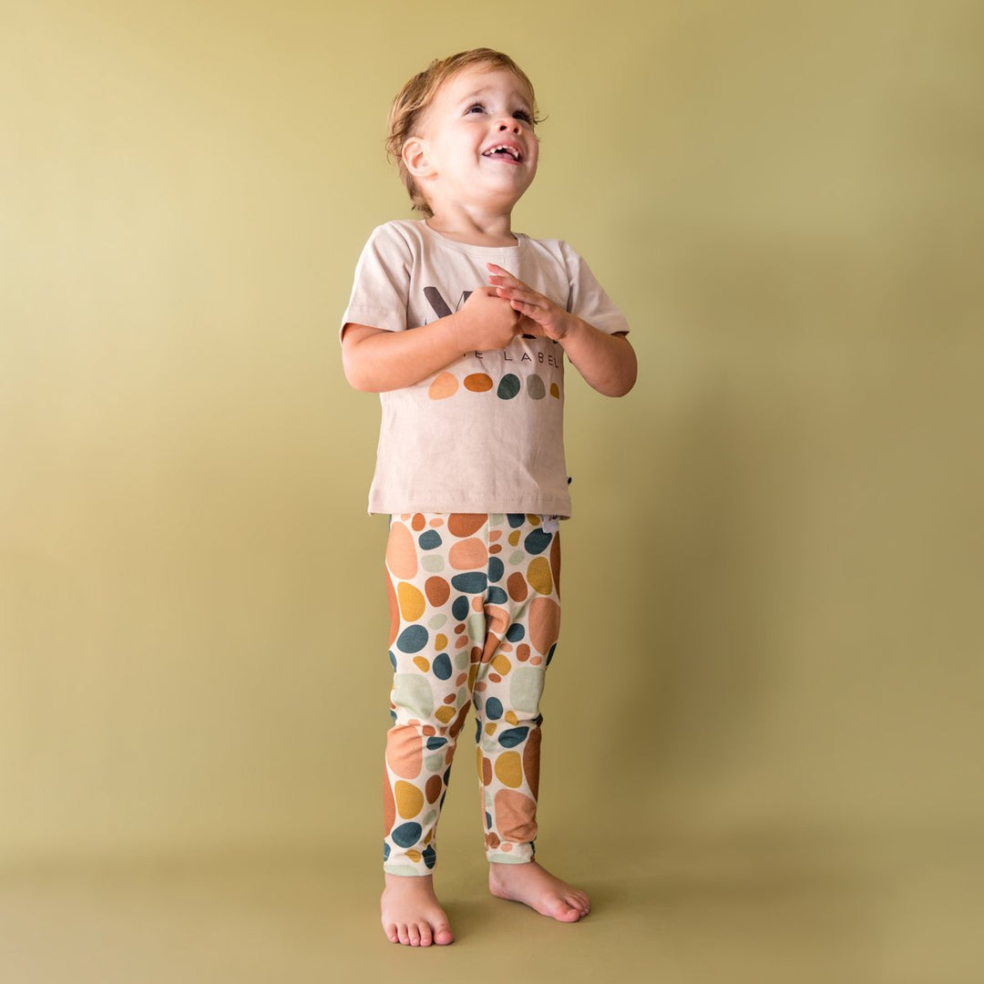 Image of child wearing stone print legging with logo tee in front of light green background.