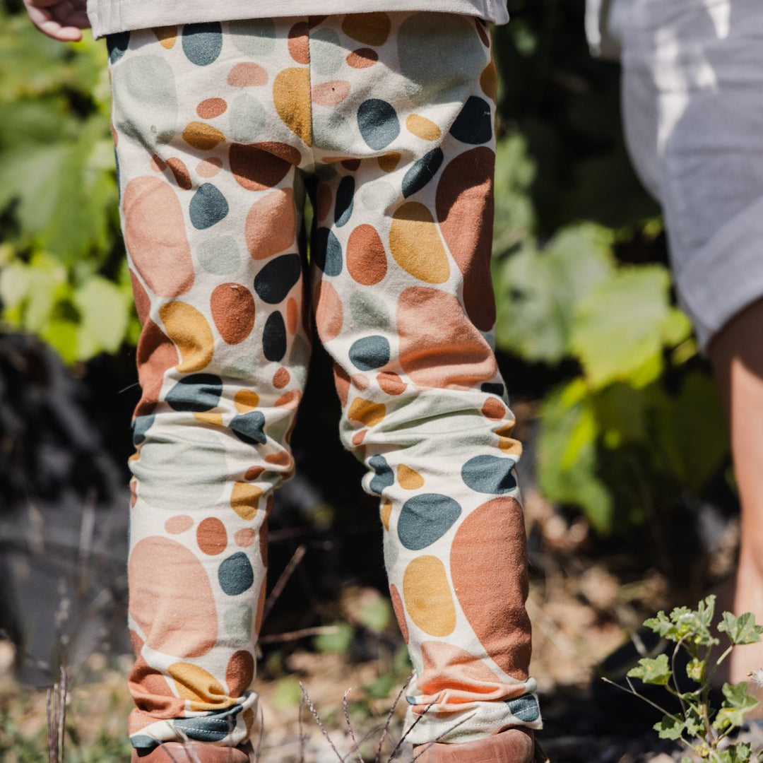 Close up image of child wearing More the label stone print leggings out in the garden.