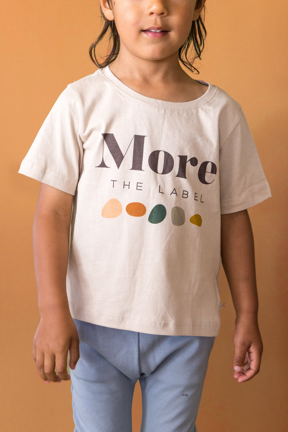 Close up image of three year old boy wearing More the label logo tee and dusty blue track pants.